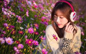 Asian girl in headphones sits in cosme colors