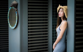 Девушка азиатка с закрытыми глазами стоит у стены 