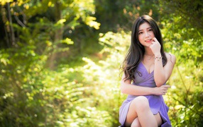 Молодая девушка азиатка сидит на лавке в парке