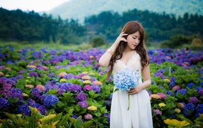 Красивая девушка азиатка в белом платье с цветами гортензии 