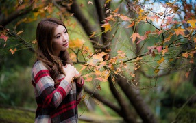 Красивая азиатка стоит у дерева