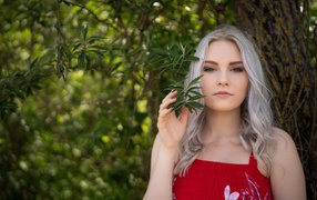 Красивая блондинка стоит у дерева 