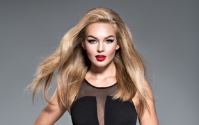 Красивая голубоглазая блондинка в черном платье на сером фоне