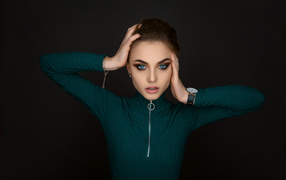 Beautiful blue-eyed girl in a green sweater on a black background