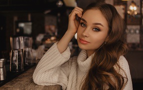 Красивая голубоглазая девушка в белом свитере в кафе