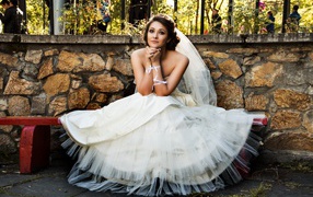 Beautiful bride in a white dress sitting on the bench