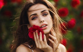 Красивая девушка шатенка с цветком у лица