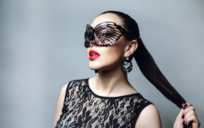 Beautiful fashion girl in black mask over gray background