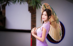 Красивая нежная азиатка в сиреневом платье с зонтом в руках