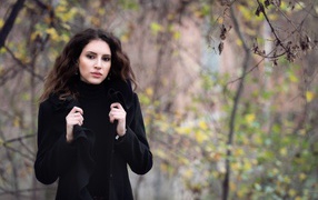 Красивая девушка в черном пальто осенью