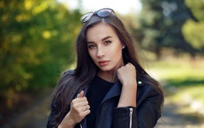 Красивая девушка в черной куртке с очками на голове