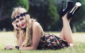 Красивая девушка в черных туфлях лежит на зеленой траве
