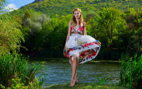 Красивая девушка в платье у реки на фоне леса 