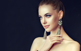 Красивая девушка с серьгами на черном фоне