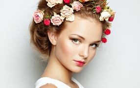 Красивая девушка с цветами в волосах на сером фоне