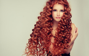 Красивая девушка с длинными рыжими волосами на сером фоне