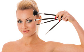 Красивая девушка с кистями для макияжа на белом фоне