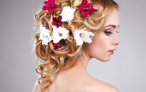Красивая девушка с цветами петунии в волосах на сером фоне