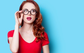Красивая рыжеволосая девушка в очках на голубом фоне