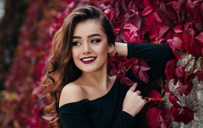 Beautiful smiling long-haired girl near the wall with decorative grapes