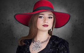 Красивая стильная девушка в красной шляпе с украшением на шее 