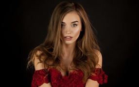 Красивая нежная длинноволосая шатенка в красном платье на черном фоне