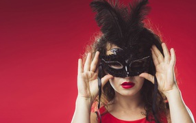 Красивая женщина в черной маске на красном фоне