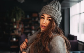 Красивая молодая девушка в пальто в вязаной шапке