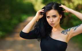 Beautiful young girl in black with a tattoo on her arm
