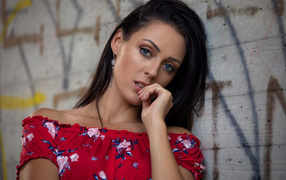 Голубоглазая брюнетка стоит в платье стоит стены