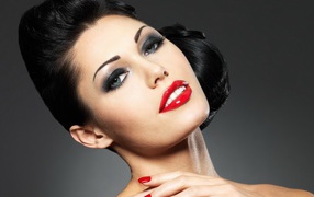 Яркая брюнетка с красными губами на сером фоне