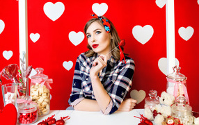 Яркая девушка за столом со сладостями на красном фоне с белыми сердечками 