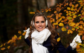 Девушка шатенка с белым шарфом стоит у дерева с желтыми листьями