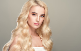 Милая длинноволосая блондинка на сером фоне