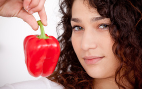 Face of a girl with a red sweet pepper in hand close-up