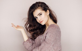 Нежная блондинка в свитере на сером фоне