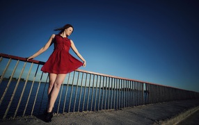 Девушка в коротком красном платье на мосту 