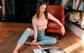 Девушка читает журнал на полу у кожаного кресла