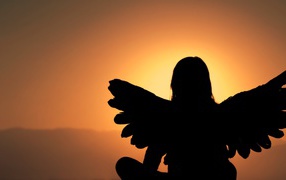 Силуэт девушки с крыльями ангела на фоне заката
