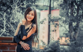 Улыбающаяся девушка азиатка в черном платье