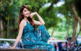 Улыбающаяся азиатка сидит на лавке