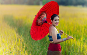 Улыбающаяся девушка азиатка с красным зонтом