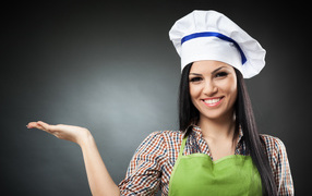 Smiling girl in chef's hat over gray background