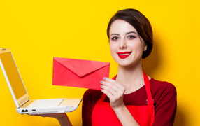 Улыбающаяся девушка с ноутбуком и конвертом в руках на желтом фоне