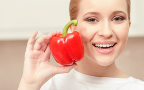 Улыбающаяся девушка с красным сладким перцем в руке