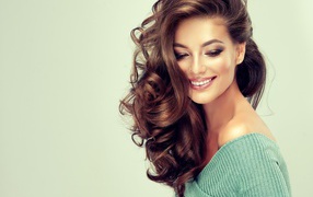 Улыбающаяся длинноволосая шатенка на сером фоне 