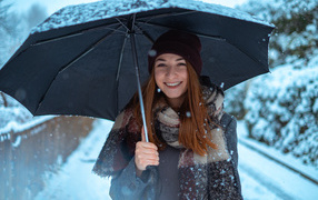 Улыбающаяся молодая девушка под зонтом зимой