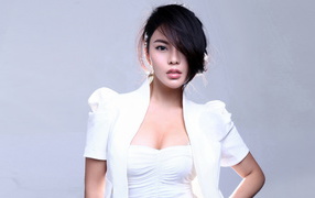 Stylish asian girl in a white suit on a gray background