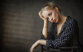 Нежная девушка блондинка сидит на стуле