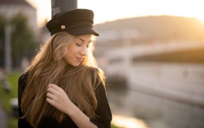 Нежная девушка в черной кепке в лучах солнца